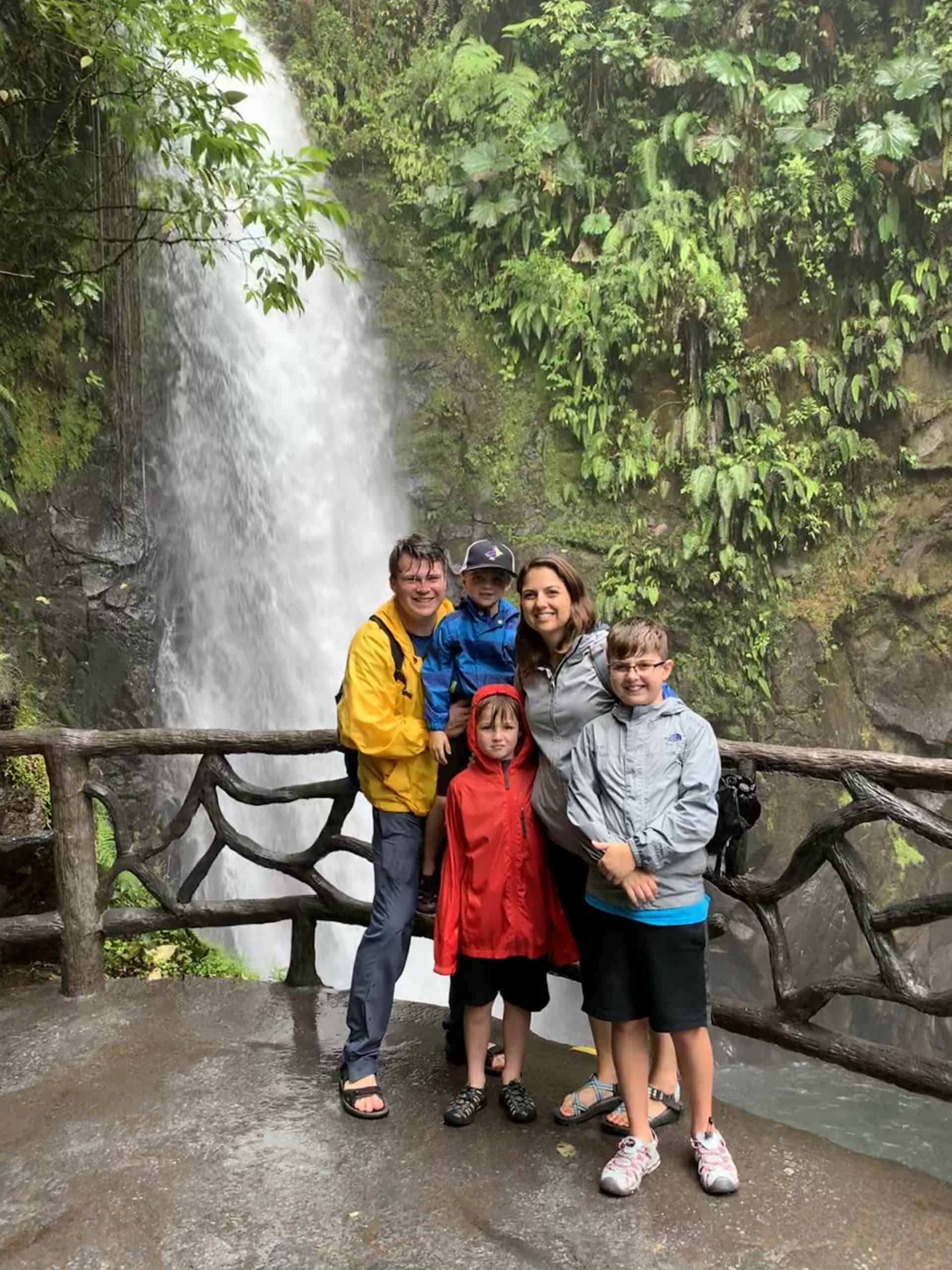 Family posing in front of waterfall at La Paz Waterfall Garden in Costa Rica
