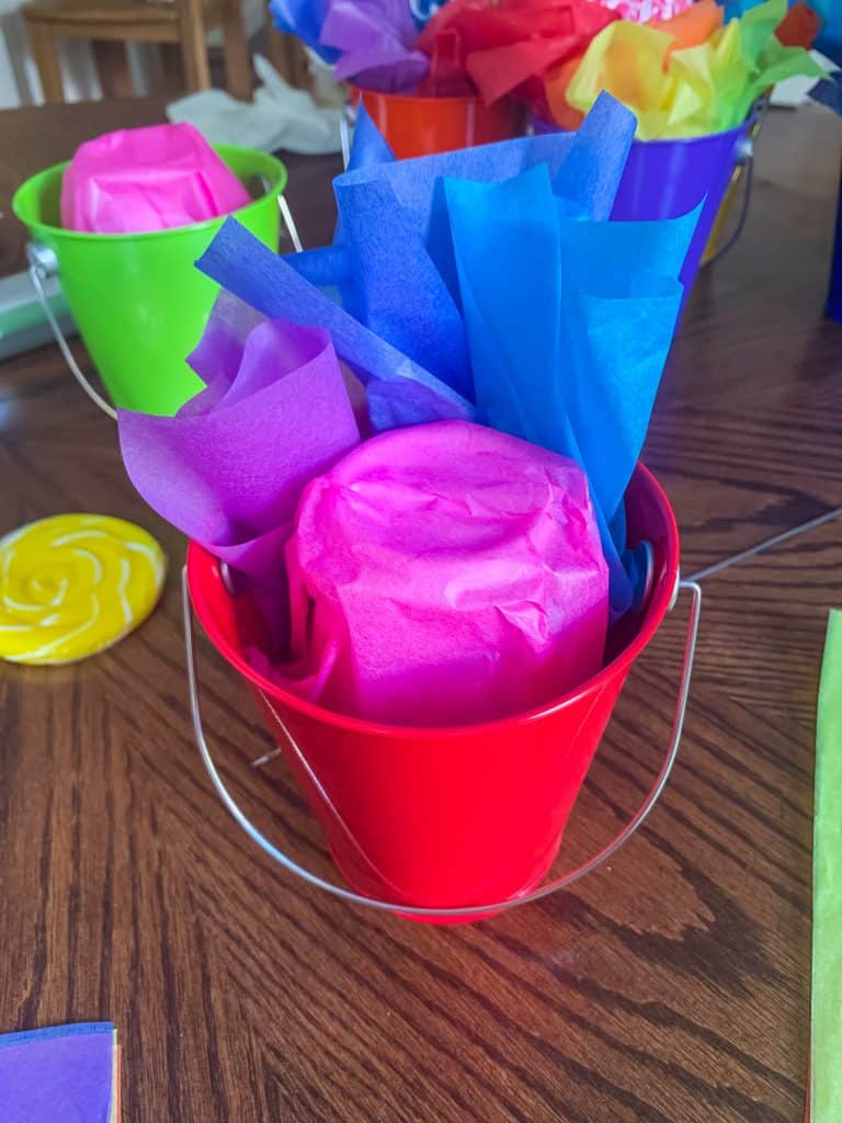 Metal favor bucket with rainbow tissue paper for lollipop centerpiece