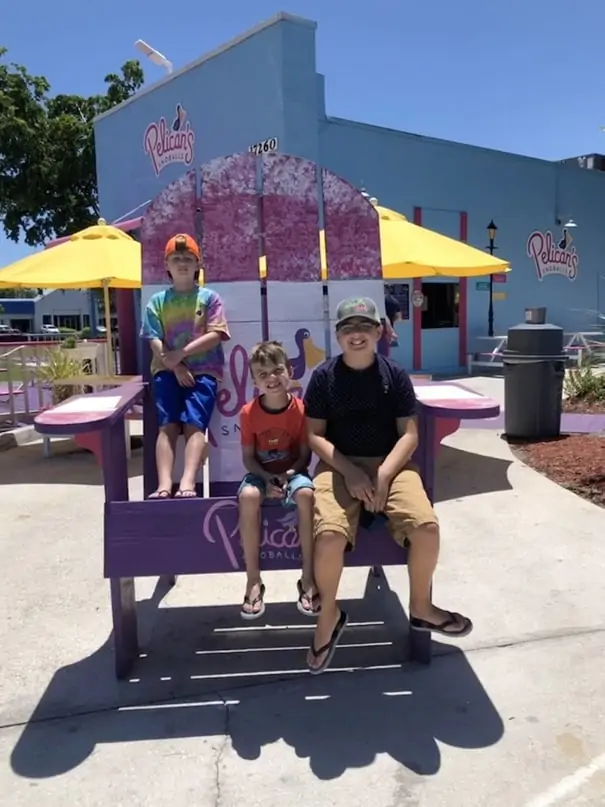boys sitting on oversized Adirondack chair at Pelicans Snoballs in Fort Myers Beach, one of our favorite things to do with kids in fort myers