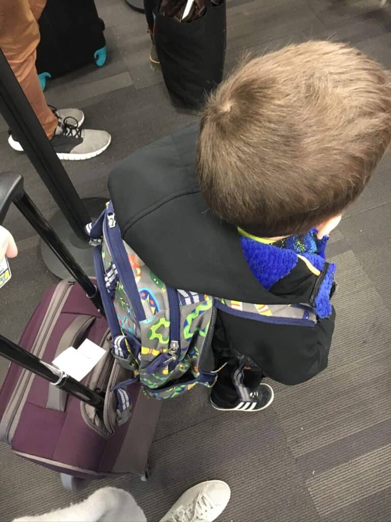 looking down on boy with brown hair and a colorful backpack on. 