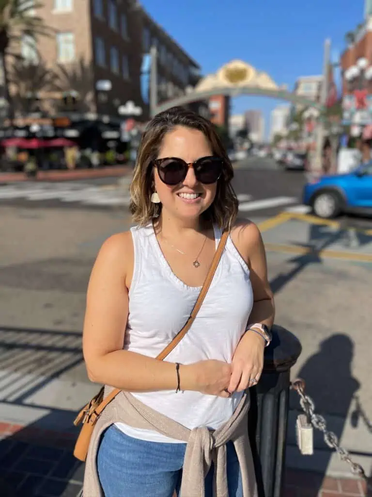 Woman in white tank top wearing sunglasses.