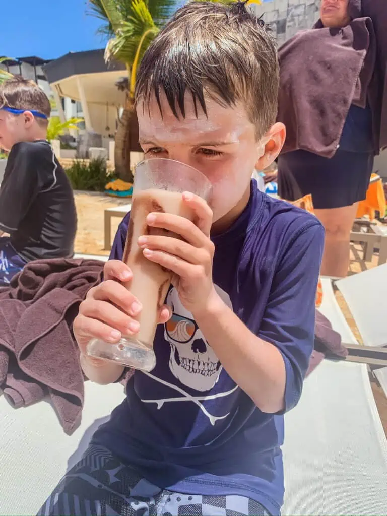 Boy sipping a drink at the beach wearing navy clothes