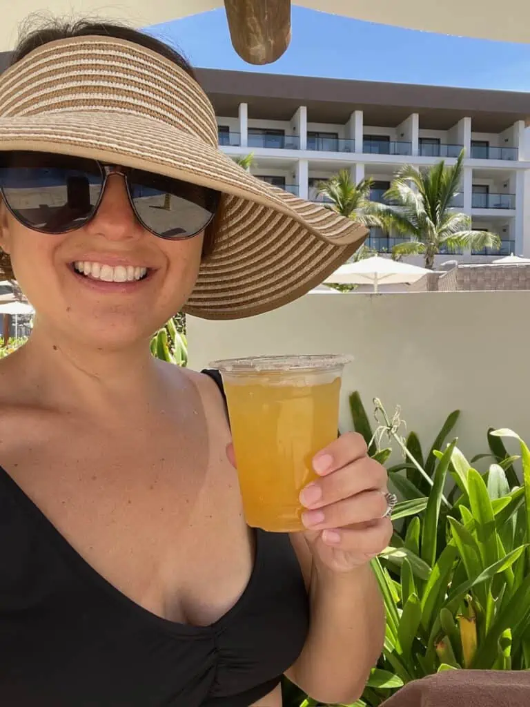 woman holding a drink with a sunhat and sunglasses on at all-inclusive resort