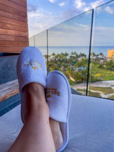 Feet in slippers from Secrets All Inclusive resort with beach in the background.