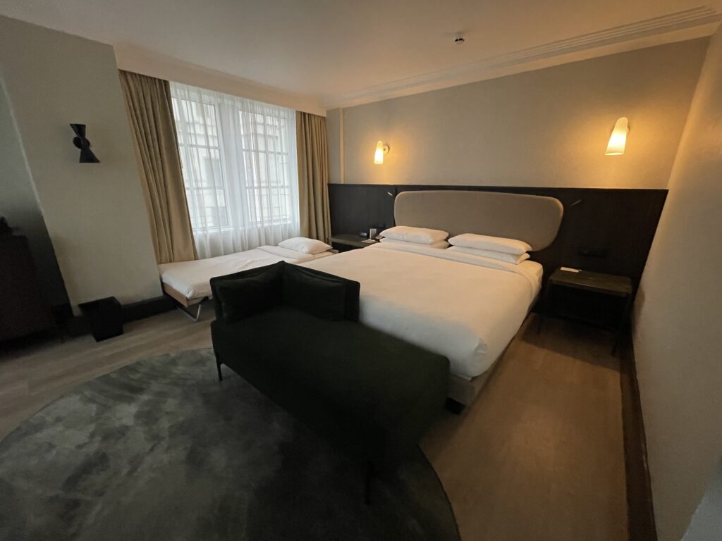 Hyatt Regency London Blackfriars King suite with rollaway bed and couch at foot of bed.